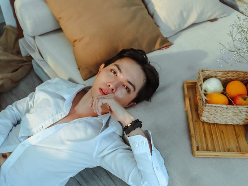 a man laying on a bed next to a basket of fruit